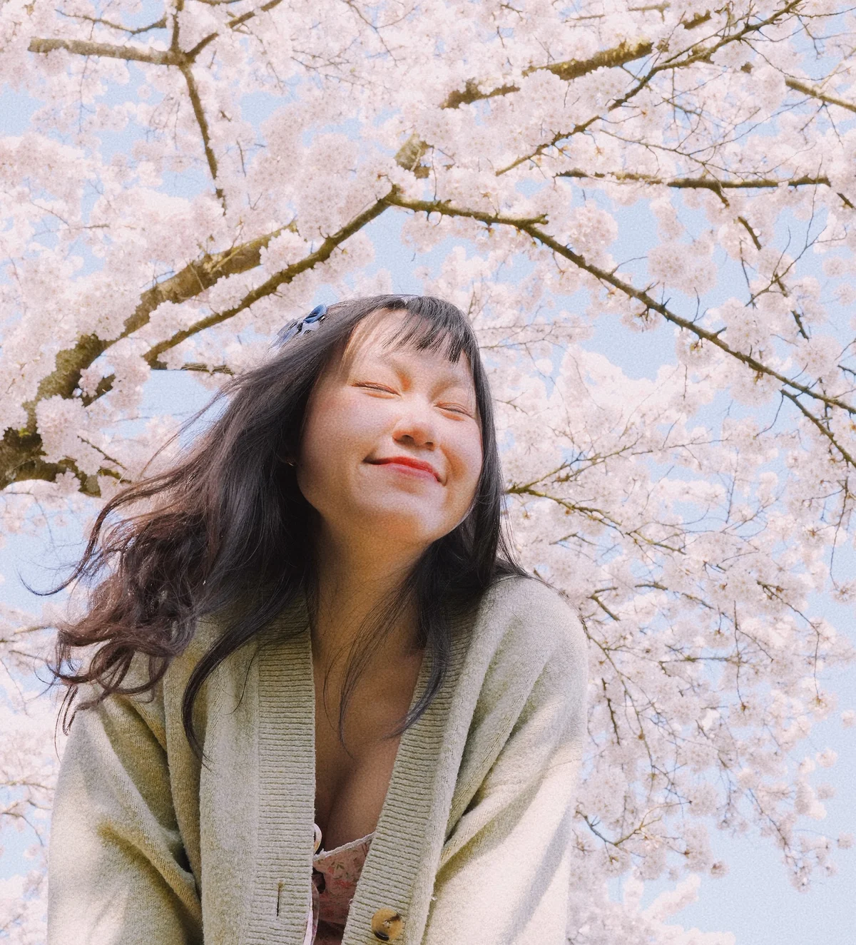 Lan smiling beneath blooming cherry blossoms